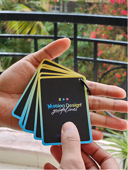 The printed Motion Design Guidelines cards, fanned out on a ring and held in one hand